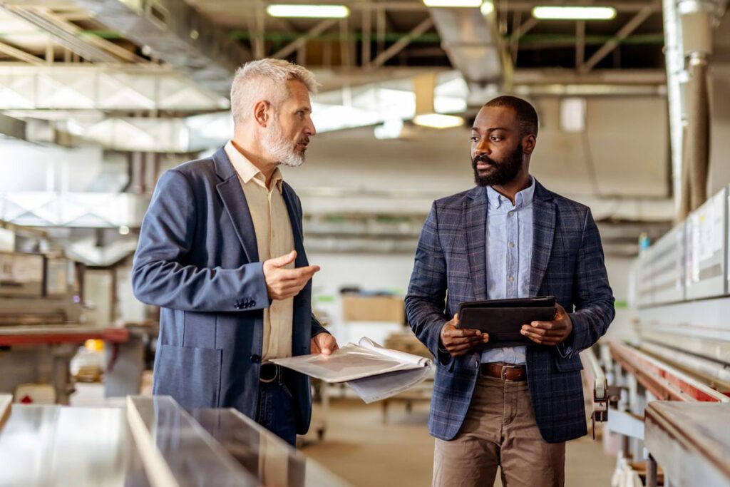 Two professionals reviewing data and discussing operations in manufacturing facility